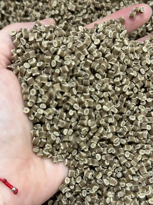 Una mano sumergida en una mezcla de pellets de agave para hacer popote.